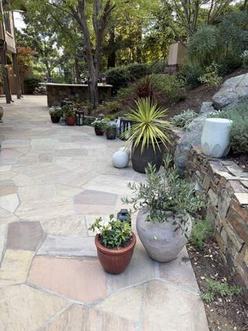Flagstone patio with stone retaining wall and potted plants