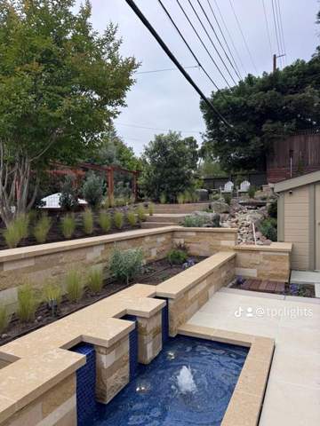 Tiered stone fountain water feature with surrounding planting