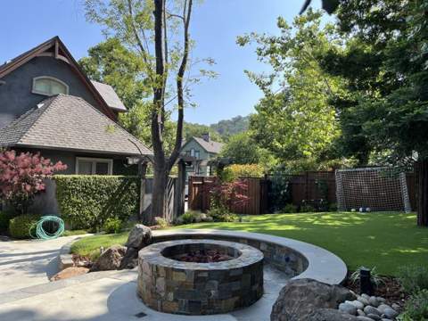 Artificial turf lawn with stone fire pit and seat wall