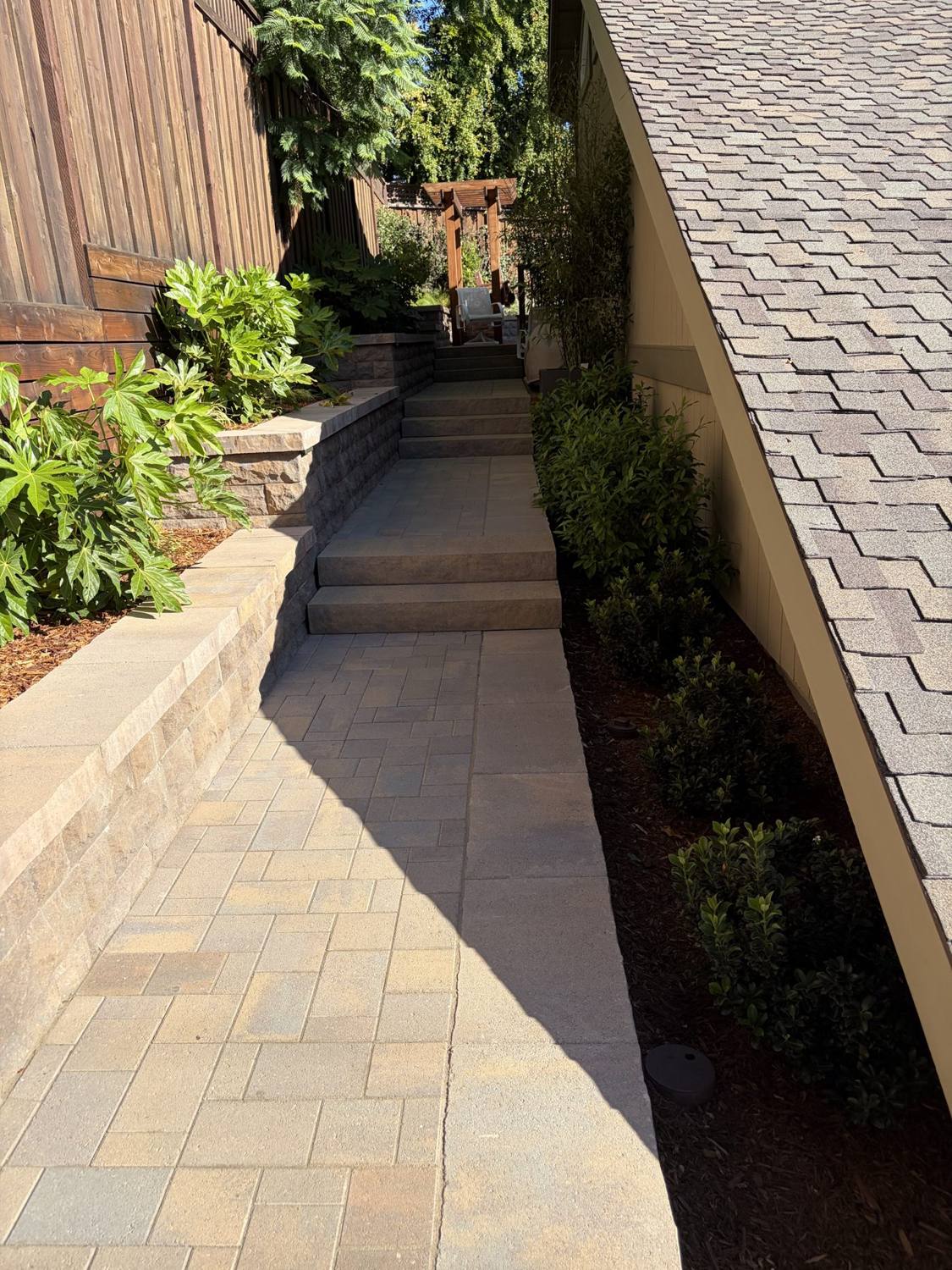 Paver walkway with retaining wall and planting beside a home