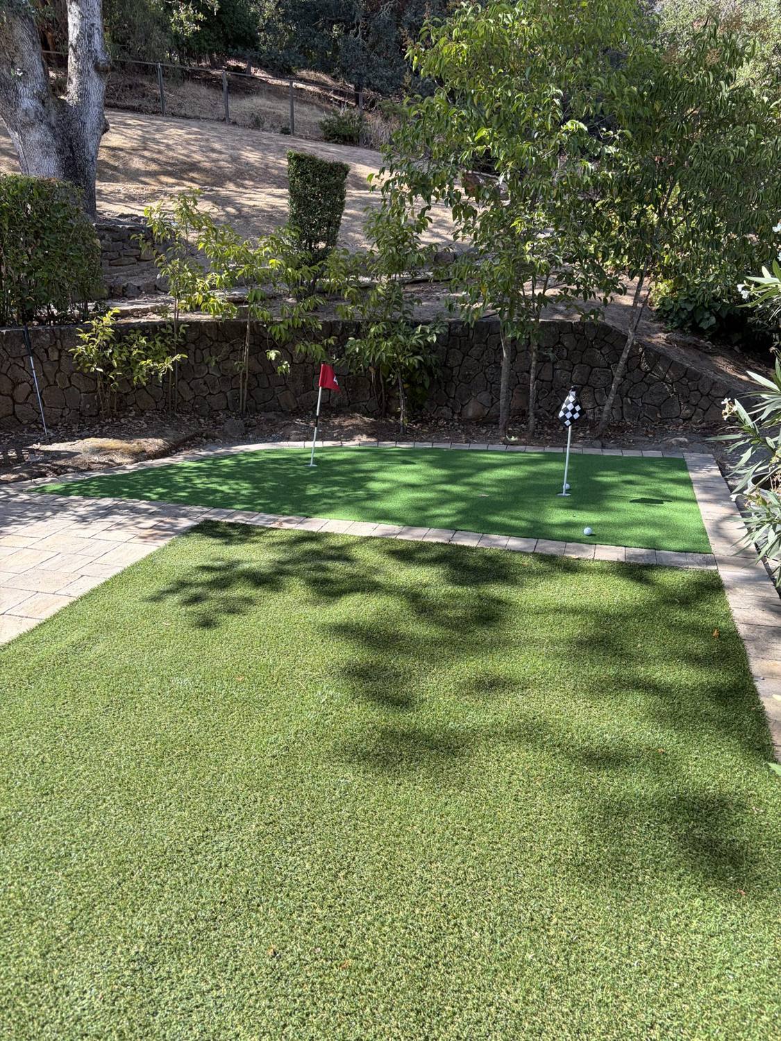 Artificial turf backyard putting green surrounded by planting